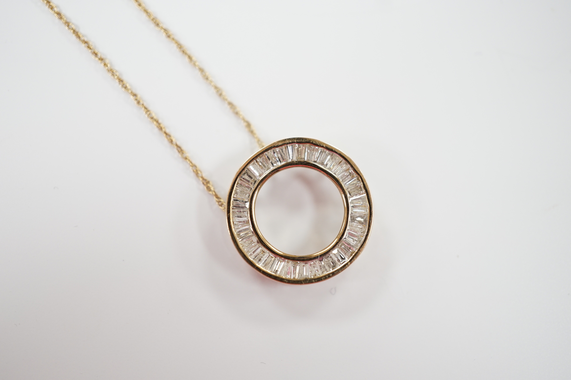 A yellow metal and trapeze cut diamond cluster set wheel pendant, 17mm, on a 9k fine link chain, 44cm, gross weight 2.1 grams.